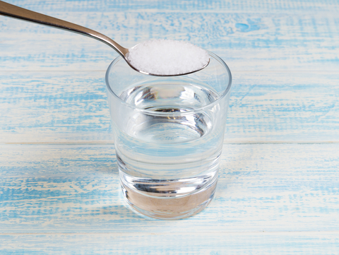 putting teaspoon of salt in a glass of water