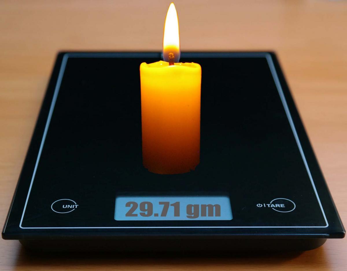burning candle on a scale weighing 29.71 grams